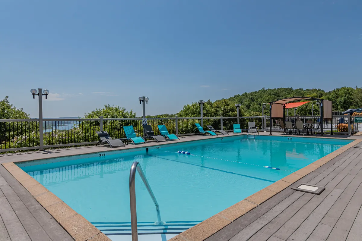 A vibrant exterior shot of the sparkling outdoor swimming pool, surrounded by lounge chairs, a canopy area for shade, and lush greenery. The pool exudes a relaxed and cheerful atmosphere, inviting guests to swim, sunbathe, or enjoy poolside gatherings.