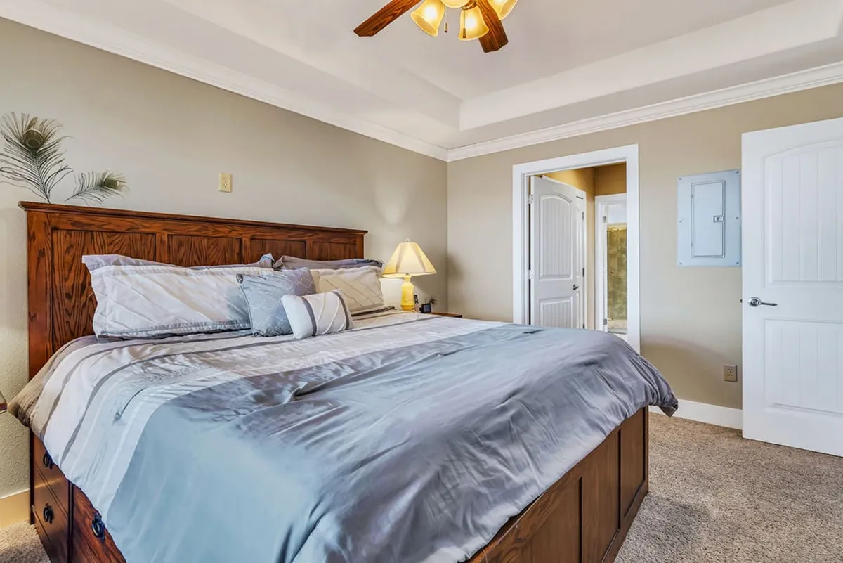 A serene bedroom with a wooden headboard, bed adorned with decorative pillows, and a warm table lamp. The overall mood is calm and restful, ideal for peaceful evenings and mornings.