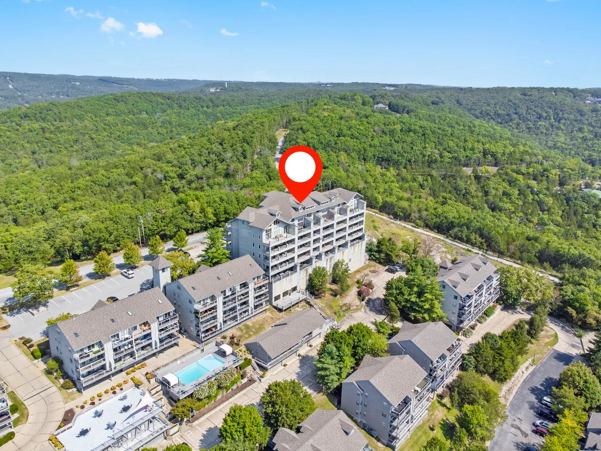 A serene exterior shot of the residential buildings surrounded by lush greenery with a sparkling swimming pool as the centerpiece. The image captures the relaxed atmosphere of the pool area, inviting families to unwind after a day exploring local attractions.