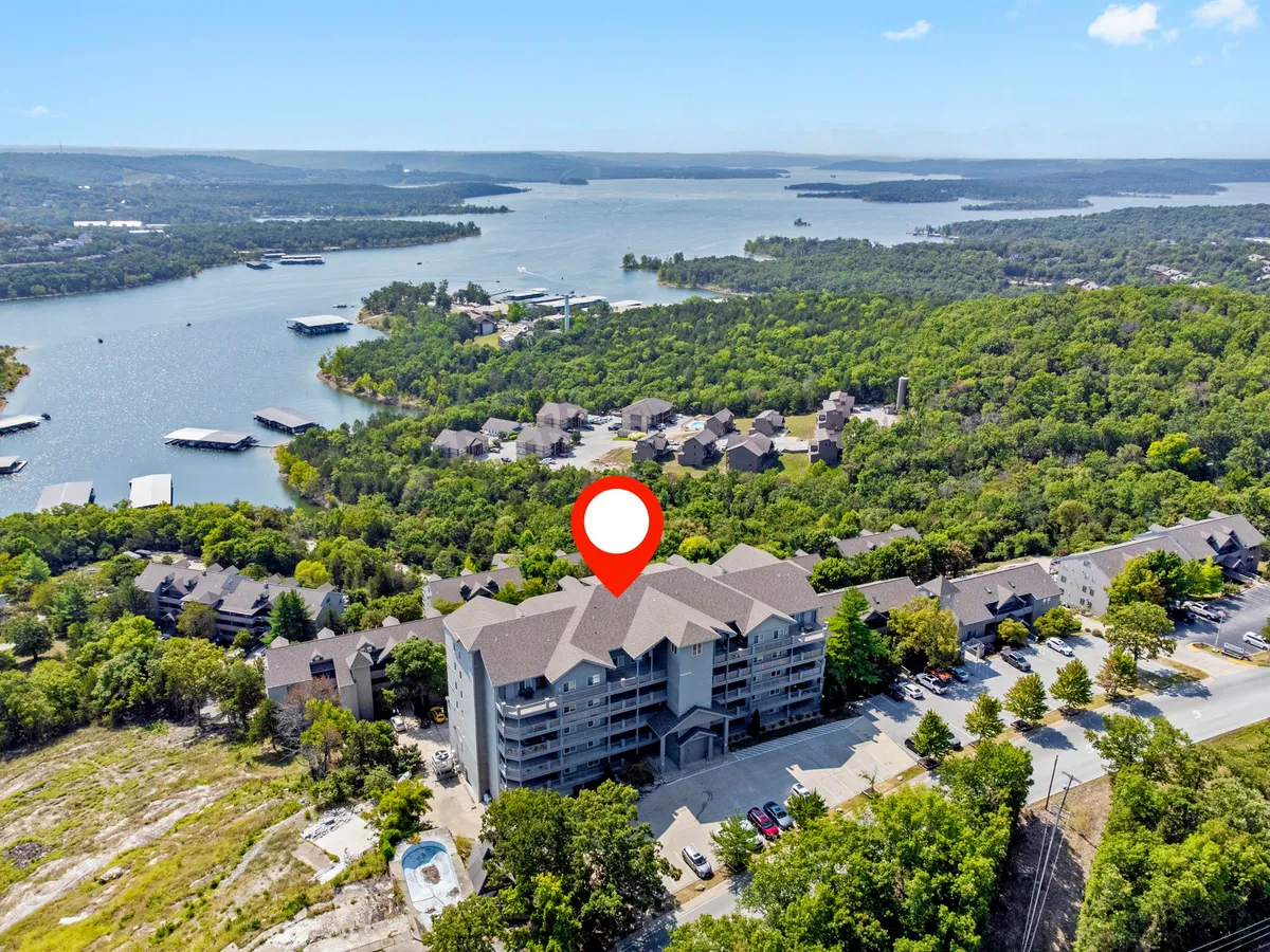 This exterior image captures the waterfront view with the apartment building set against lush greenery, offering a tranquil, scenic escape. The scene highlights opportunities for outdoor activities like boating, hiking, and relaxing by the water, with the building’s proximity to the lake in clear view.